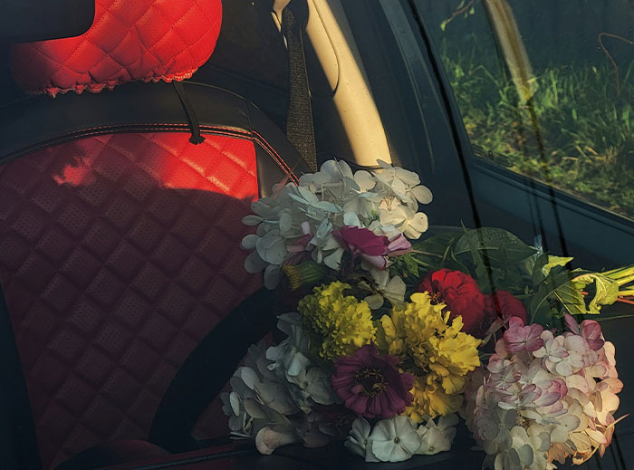 A bouquet of flowers on a car seat with red upholstery, capturing a "nice guy" gesture.