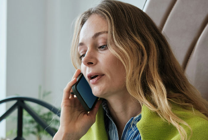 Woman talking on the phone indoors, representing creepy story themes about giving "nice guys" a chance.