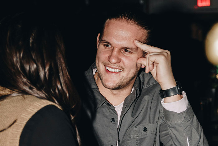 Man smiling at woman in dimly lit setting, representing nice guys interacting.