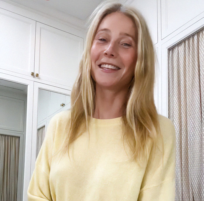 Blonde woman in a yellow sweater smiling, standing in a white room with cabinets, addressing feud rumors.