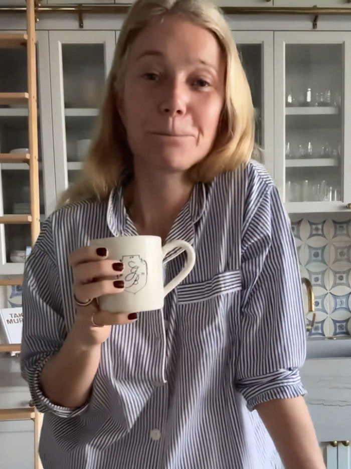 Gwyneth Paltrow in a kitchen holding a mug, wearing a striped shirt, addressing feud rumors.