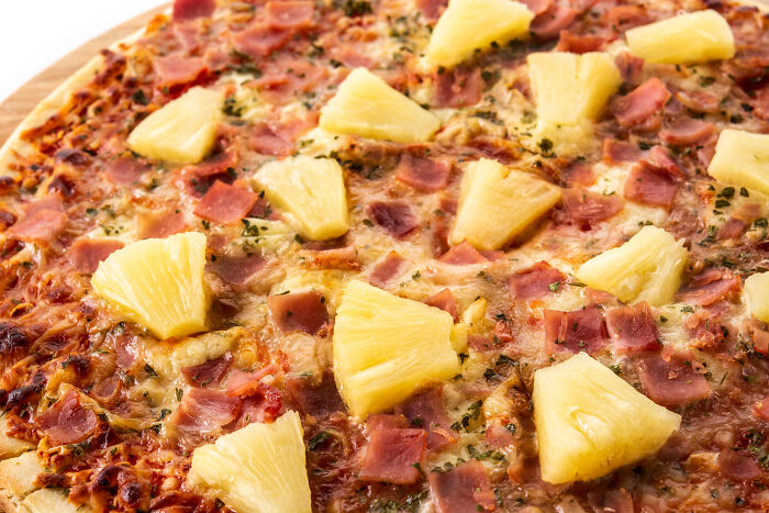 Pizza with pineapple and ham, a dish often receiving more hate than deserved, topped with cheese and herbs.