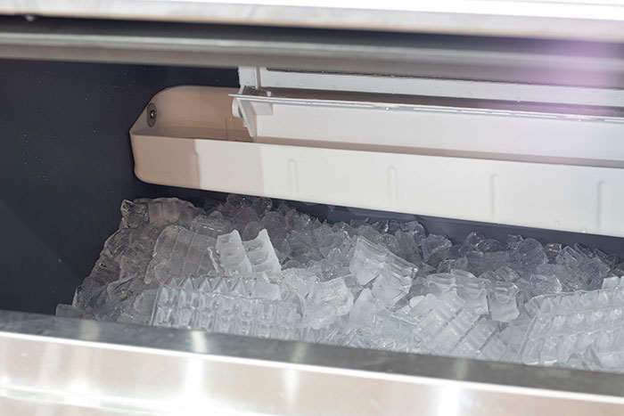 Ice machine in restaurant kitchen, filled with ice cubes, illustrating cleanliness issues seen by staff.