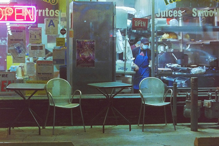 Restaurant kitchen viewed from outside, showing a worker in a mask, highlighting hidden aspects of restaurant operations.