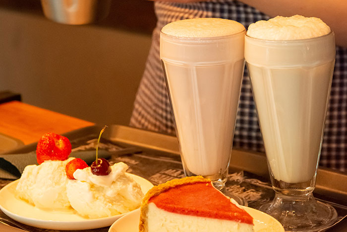 Milkshakes with ice cream and cheesecake on a tray, highlighting restaurant kitchens and dessert presentation.