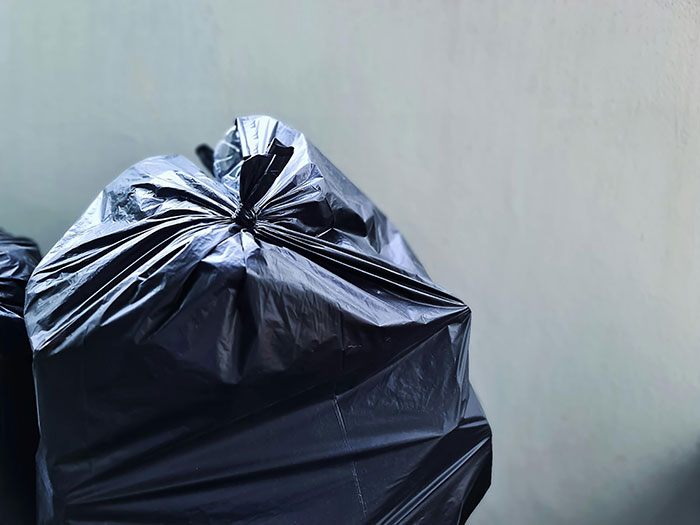 Black garbage bags stacked, reflecting restaurant kitchen waste issues.