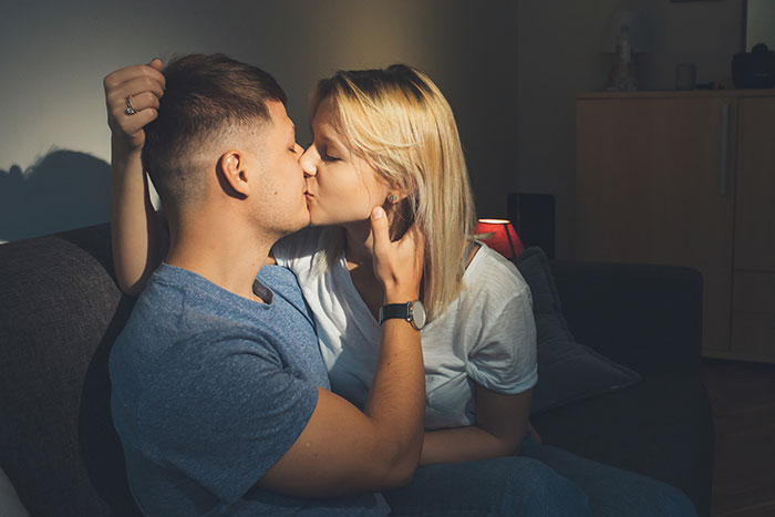 A couple kissing on a couch, defying the statement of being "just a friend".