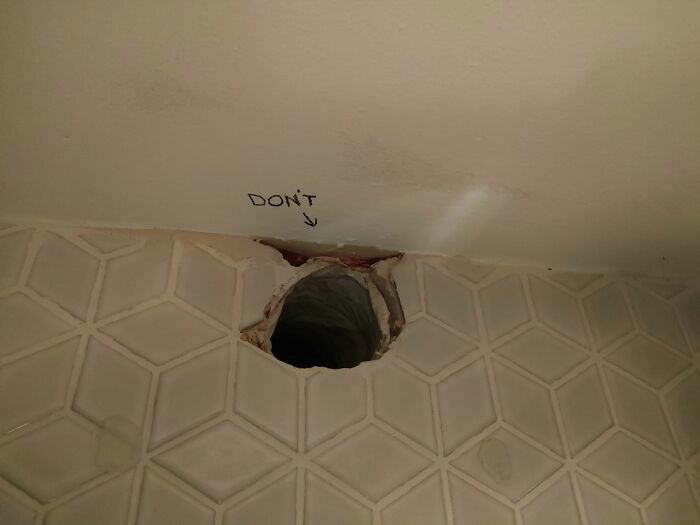 Hole in tiled wall labeled "DON'T," indicating a big mistake aftermath.