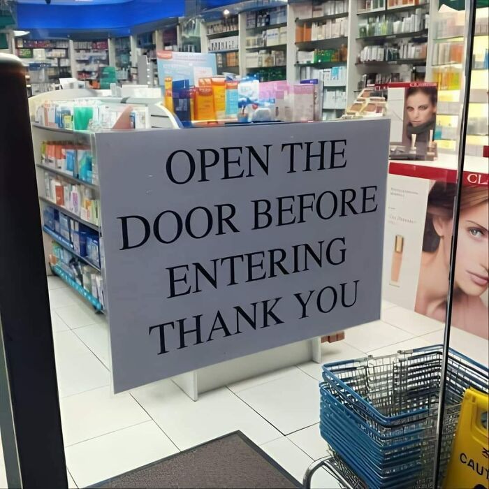Sign in a store says "Open the door before entering," showcasing a warning sign mistake.