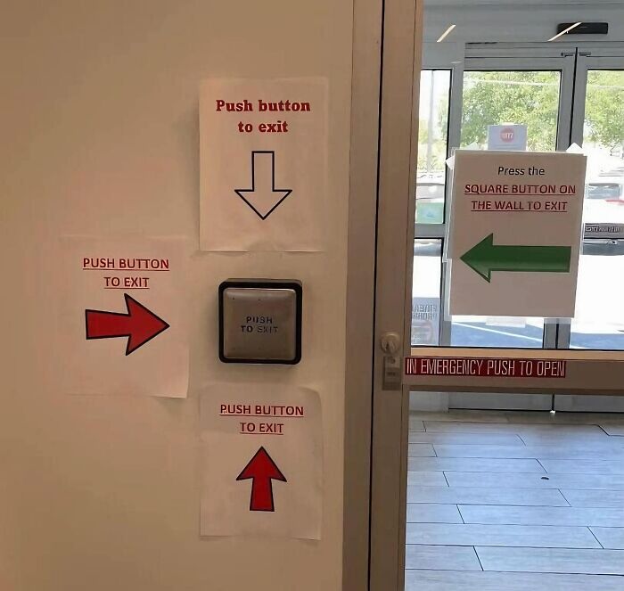 Confusing exit signs with arrows pointing in different directions next to a push button.