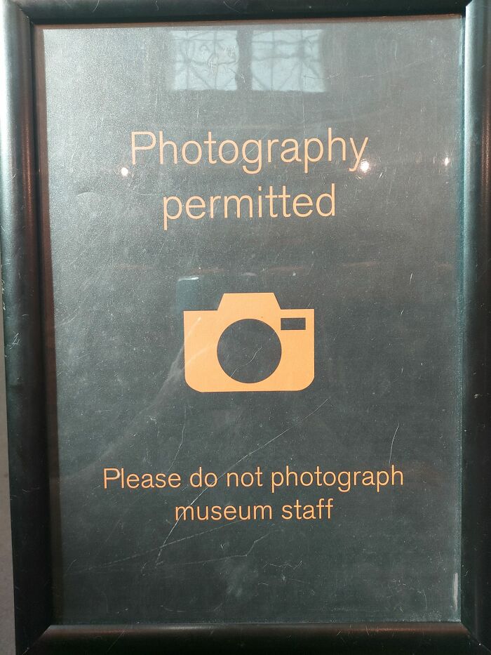 Sign saying photography is permitted but not of museum staff; an aftermath of someone's big mistake.