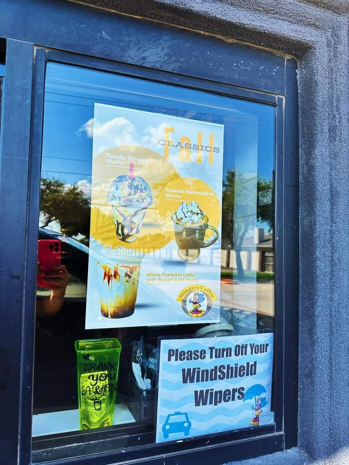 Drive-through window with coffee posters; sign warns "Turn Off Windshield Wipers" indicating possible mistake aftermath.