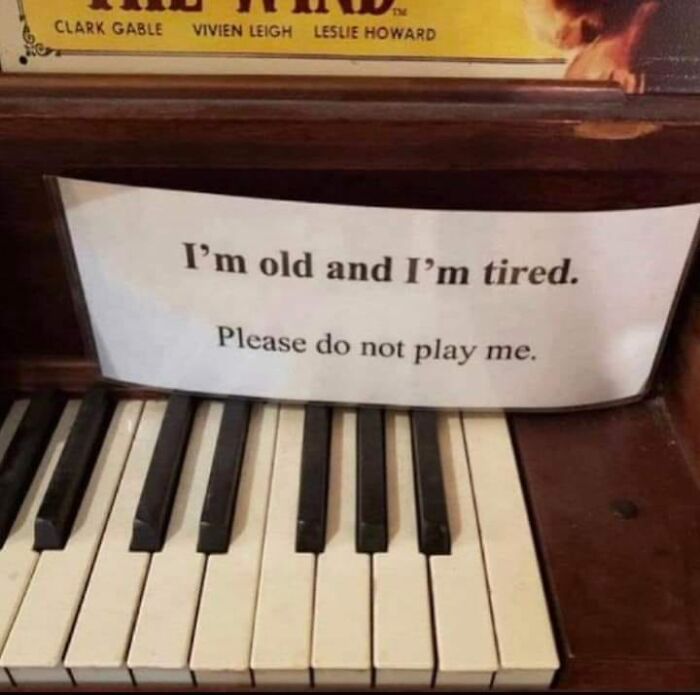 Old piano with a humorous sign, capturing a warning sign of someone’s big mistake.
