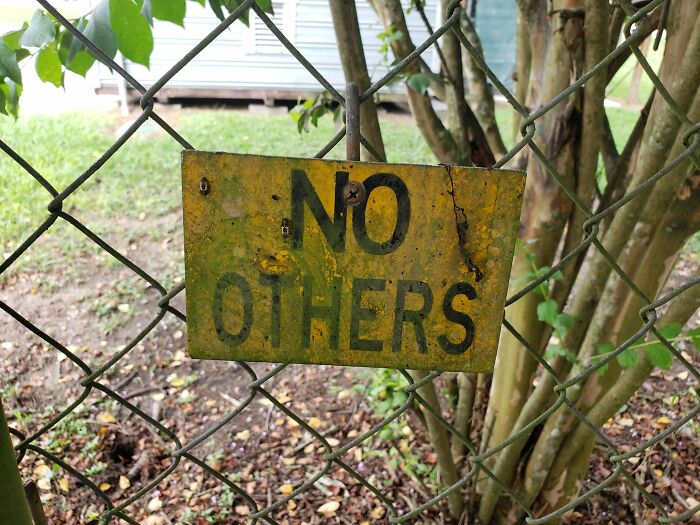 Sign on a fence reads "No Others," suggesting a warning sign.
