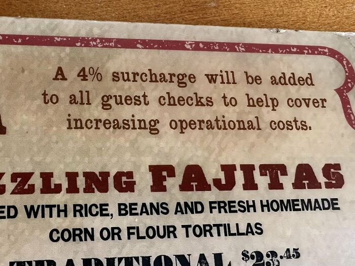 Menu sign with surcharge warning, mentioning increased operational costs for sizzling fajitas.
