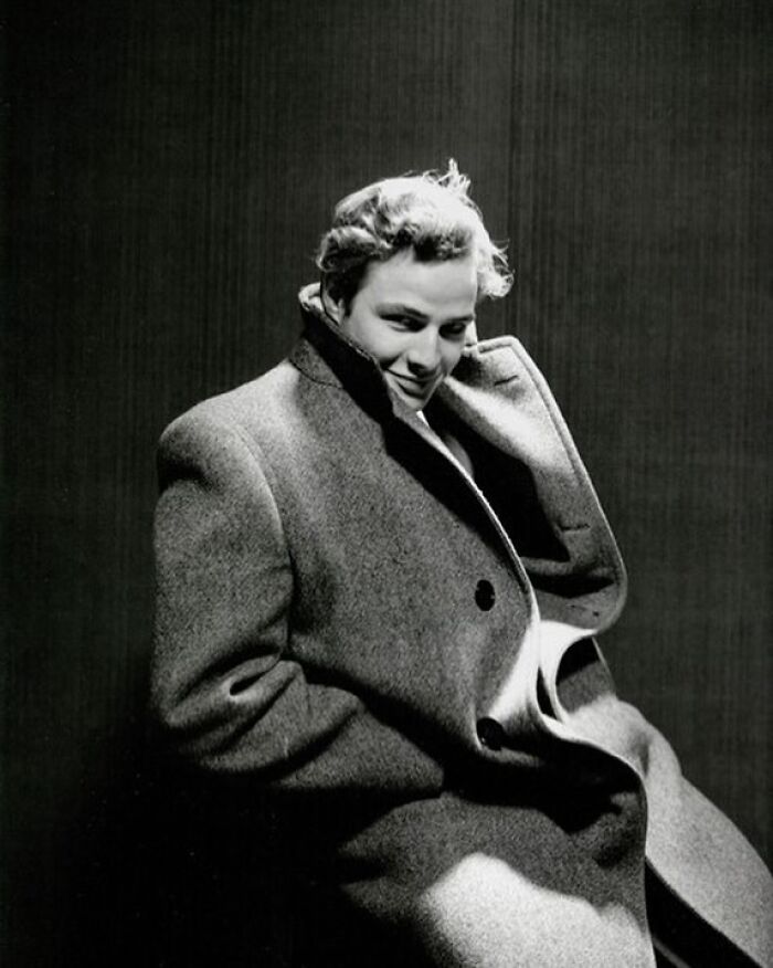 Person in a large coat with a subtle smile, representing forgotten corners of history.