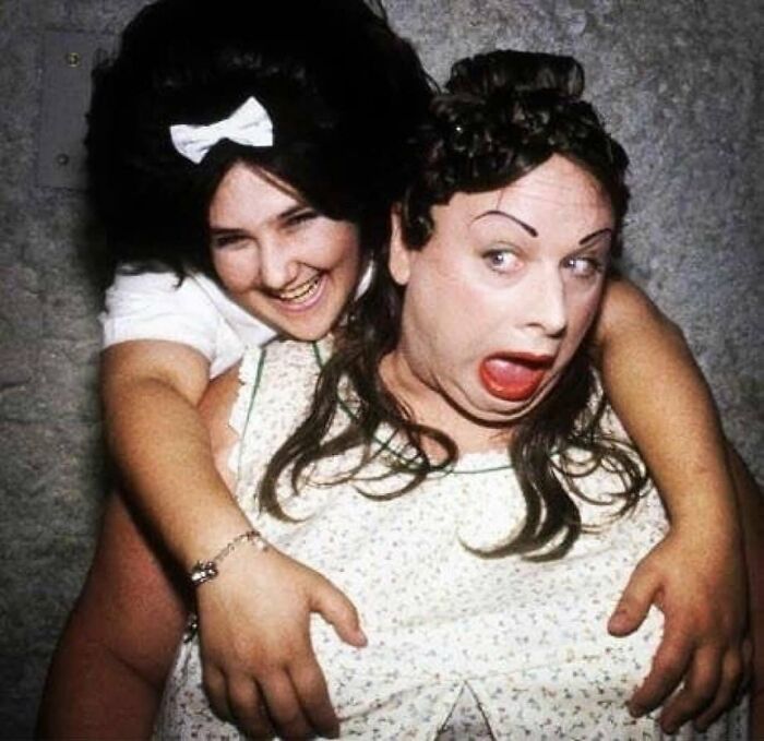 Two people in vintage attire sharing a playful moment, embodying forgotten corners of history.