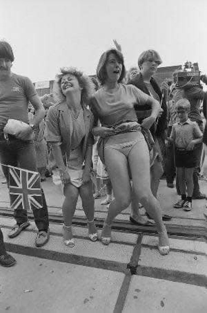 People celebrating in a festive street scene with a Union Jack flag, capturing a forgotten corner of history.