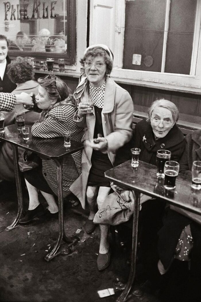 Women in vintage attire enjoying drinks in a pub, capturing a forgotten corner of history.