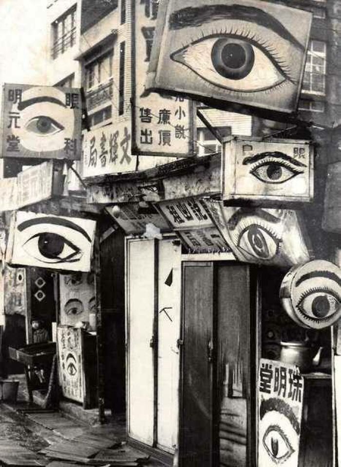 Vintage storefront with numerous signs featuring large eyes, representing forgotten corners of history.