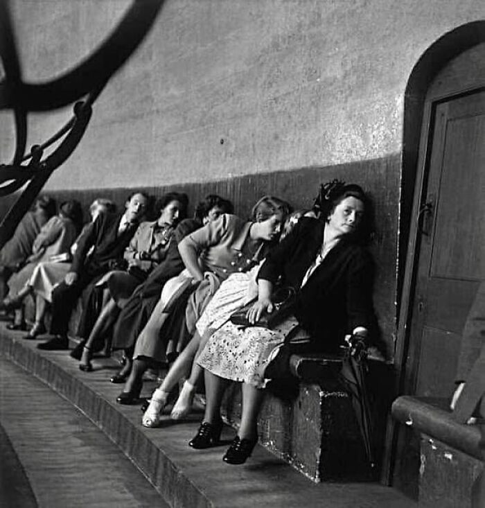 People seated in a curved row, resting against a wall, capturing forgotten corners of history.