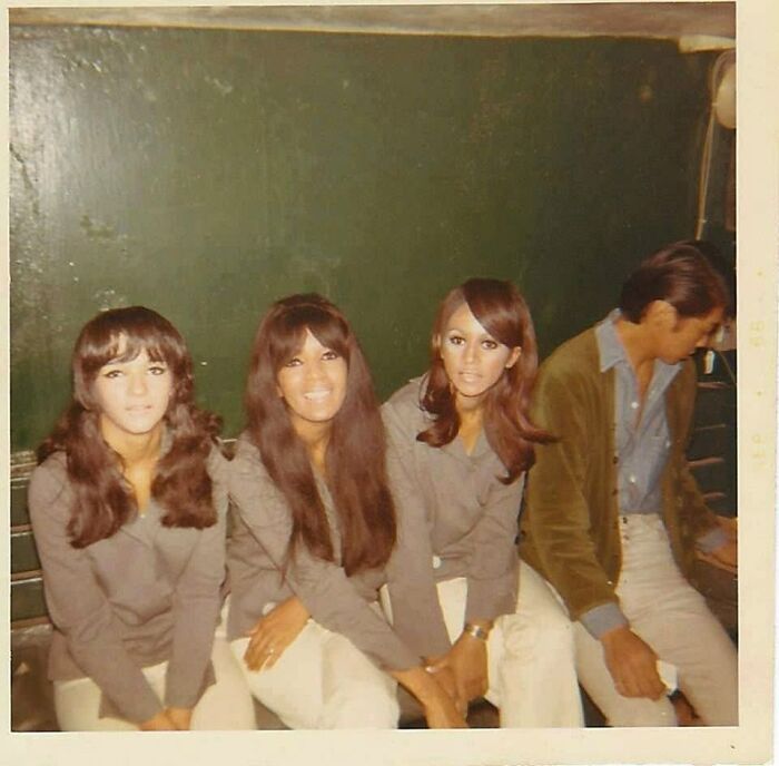 Women sitting together with a man in vintage attire, capturing a moment from forgotten corners of history.