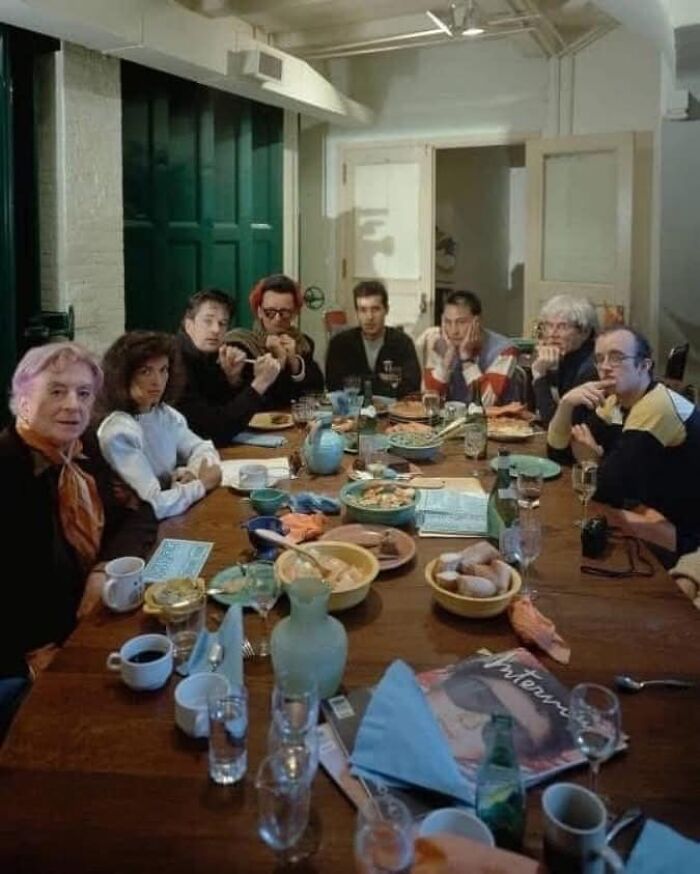 People around a dining table with colorful dishes, capturing a moment from forgotten corners of history.