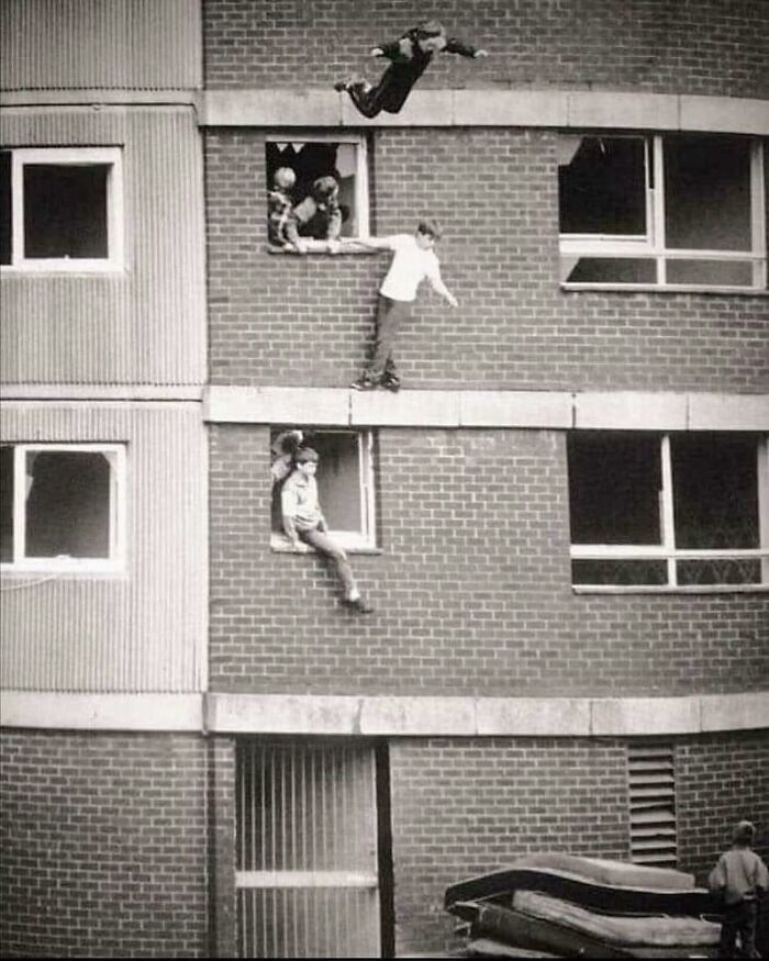Daredevils jumping from windows of a brick building, captured in a forgotten corner of history.