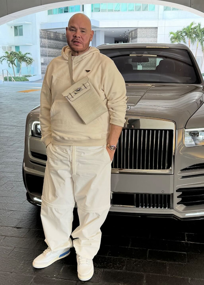 Man in cream outfit poses in front of luxury car, highlighting Hollywood beauty standards debate. Man in cream outfit poses in front of luxury car, highlighting Hollywood beauty standards debate.