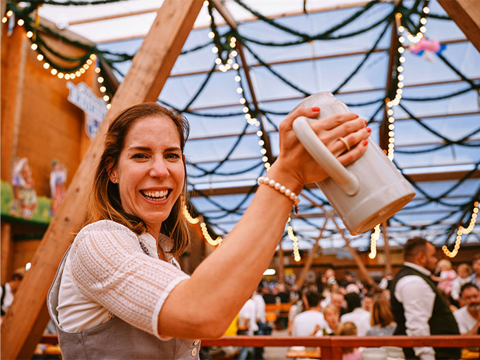 Smiling woman at a festive event holding a large mug, with decorations in the background, addressing experiences with dating challenges.