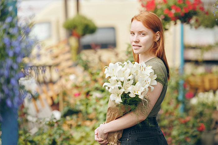 Woman holding flowers in a garden setting.