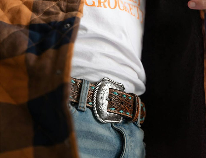 Close-up of a decorative belt with silver buckle, worn with jeans and a white shirt, highlighting dating fashion style.
