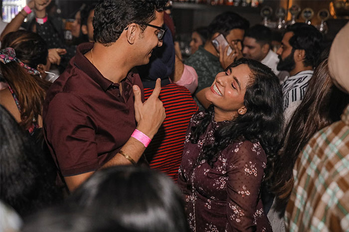 A woman smiling at a man in a crowded bar, dealing with dating challenges.