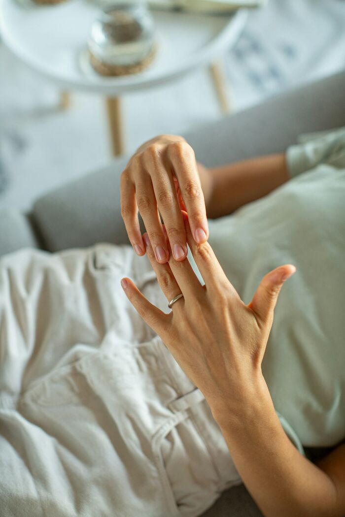 Close-up of a hand removing a ring, symbolizing rejection in relationships.