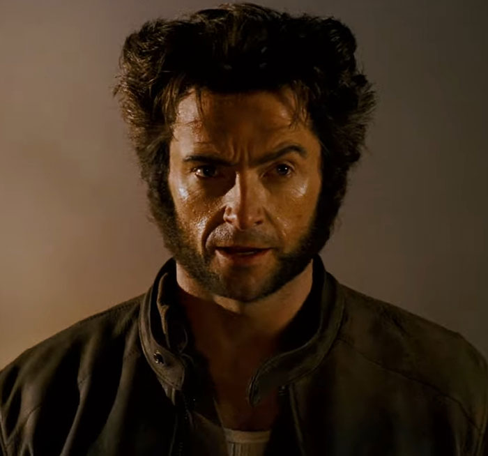 Hugh Jackman with dramatic facial makeover, wearing a leather jacket, captures a '70s vibe.