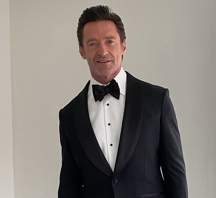 Man in a tuxedo, styled hair, posing confidently in a well-lit room, fitting the '70s Pawn Star' vibe.