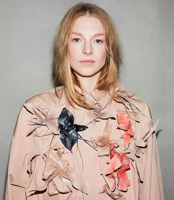 Transgender actor in floral-patterned shirt, posing confidently against a neutral background.