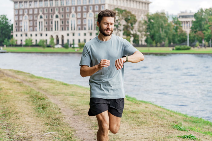 Man jogging by a river, checking his smartwatch. Man jogging by a river, checking his smartwatch.
