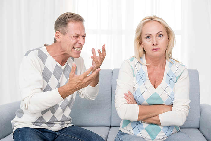 Man frustrated with woman on couch, possibly debating a gift choice, related to husband gift vacuum wife topic.