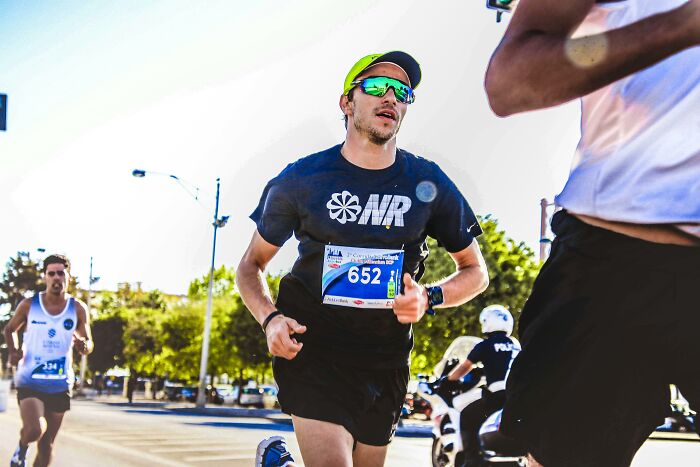Man in running gear with yellow cap participating in a race, focusing on running.