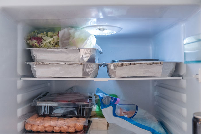 Foil food containers and groceries in a fridge, related to a husband's comment on lunch being "absolutely disgusting. Foil food containers and groceries in a fridge, related to a husband's comment on lunch being "absolutely disgusting.