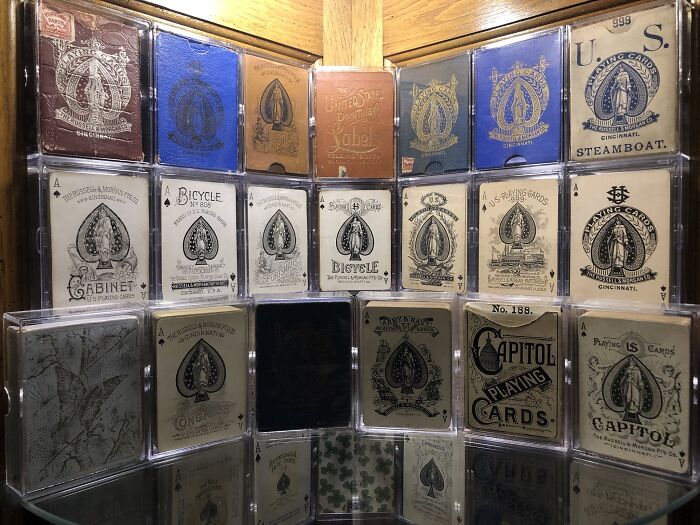Vintage playing cards in a wooden display case, showcasing rare designs and historical packaging.
