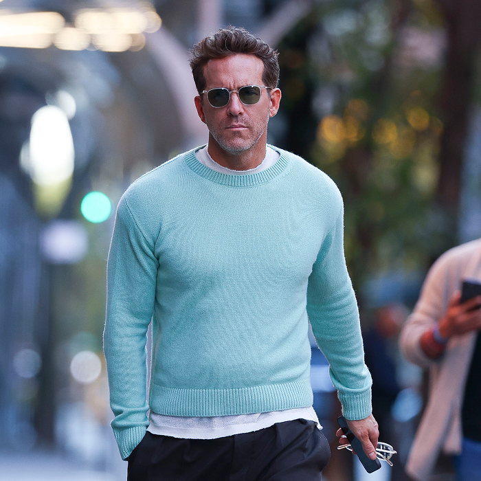Ryan Reynolds in sunglasses and mint sweater walking outside, representing business success and wealth. Ryan Reynolds in sunglasses and mint sweater walking outside, representing business success and wealth.
