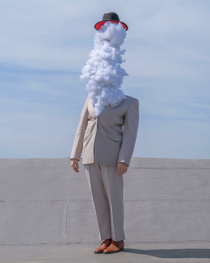 Surreal photograph by Ben Zank of a solitary figure in a suit with a cloud for a head, wearing a hat.