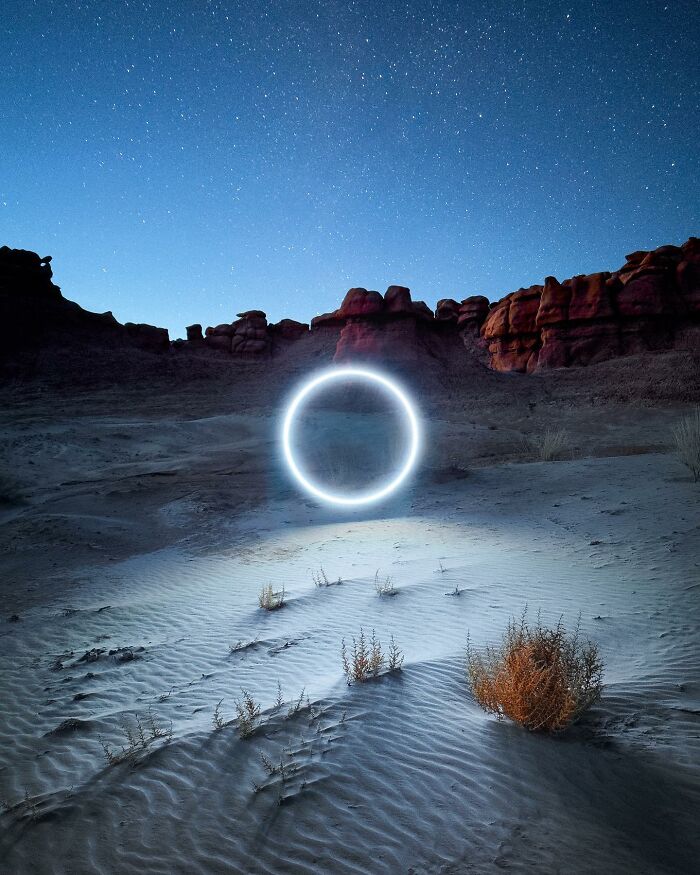 Drone lighting creates a glowing circle in a desert landscape under a starlit sky.