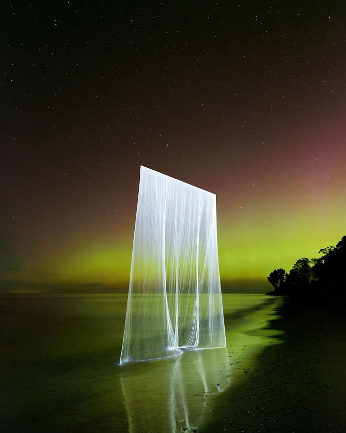 Drone-lit natural landscape with glowing rectangular light against starry sky.