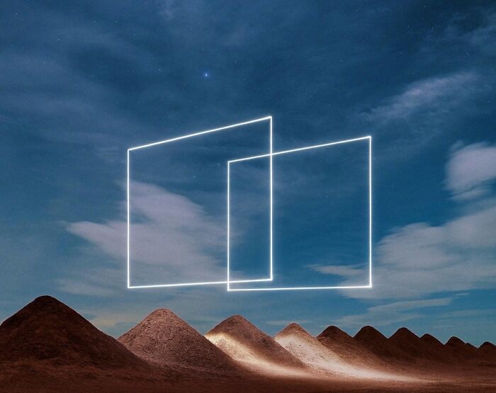 Drone-lighting casts geometric shapes over a desert landscape under a starry night sky.