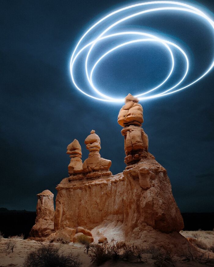 Drone-lighting landscape photography featuring sandstone formations under illuminated circular trails in the night sky.