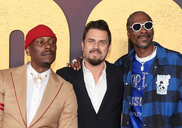 Three men posing together, Snoop Dogg wearing sunglasses and a blue jacket, representing aspects of Snoop Dogg's net worth.