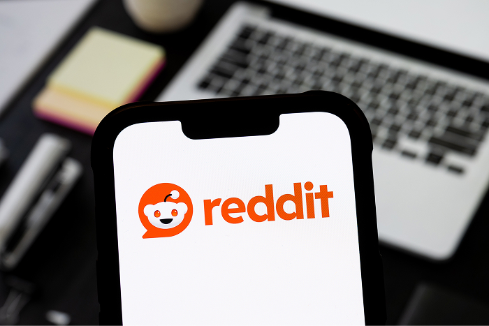Smartphone displaying Reddit app logo, symbolizing online communities and discussions about Snoop Dogg&rsquo;s net worth.